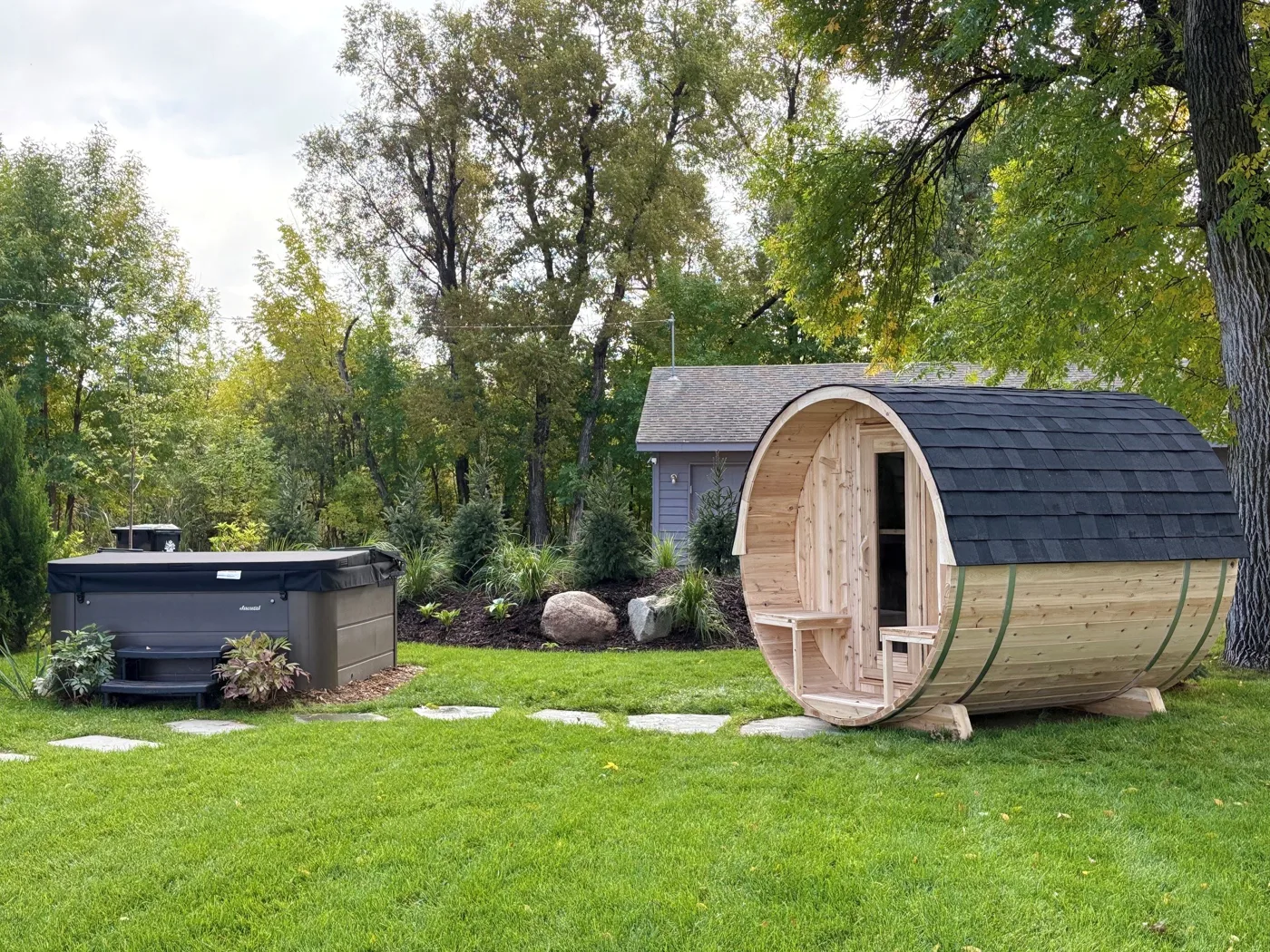 Barrel sauna and hot tub on the lawn among the pines